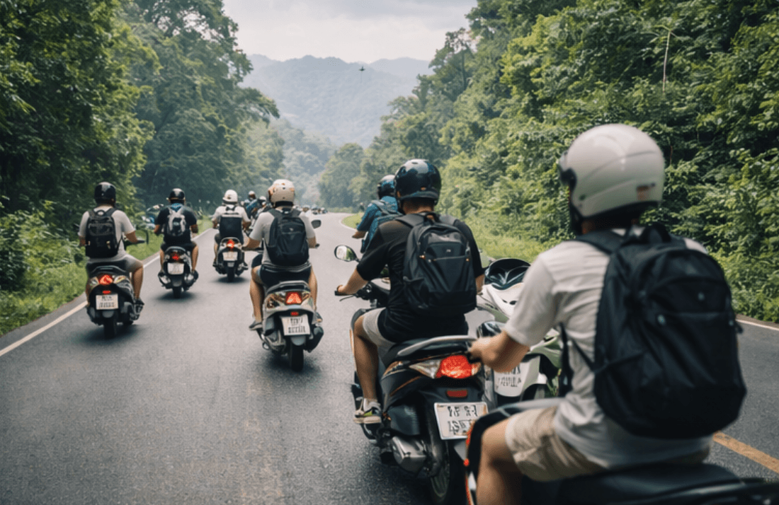 Scooter riders with backpacks travel along a winding road through a lush green mountain forest.